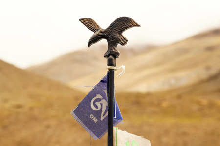 Iron figure of the eagle with the flag of Om with the background of the mountainsの写真素材