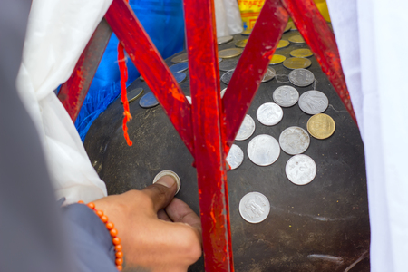 Indian man hand putting coin on stone blessing. Indian people believe that it is for good luck.の写真素材