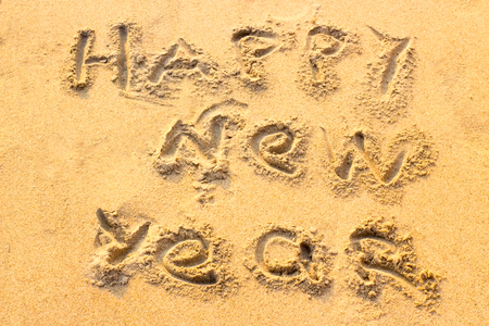 Handwriting Happy New Year on the sand. Christmas conceptの写真素材