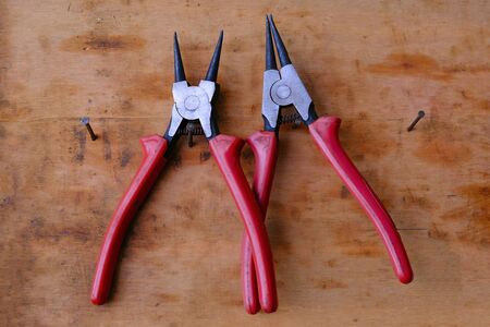 Tongs pliers with red plastic handles hang on nails on the banner canvas. Tools in the workshop.の写真素材