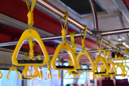 Yellow plastic handles on a metal handrail on the bus. Security concept.の写真素材