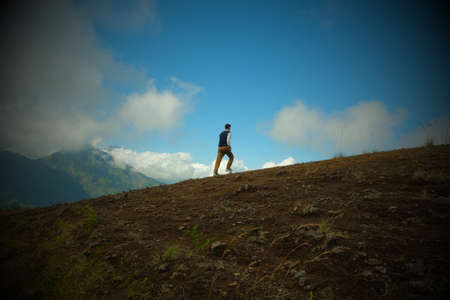 A man climbs a mountain in the clouds. Processing photos with a vignette.の写真素材