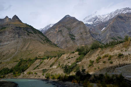 A small car is moving along a serpentine path between the Himalayan Mountains. Small against a huge background.の写真素材