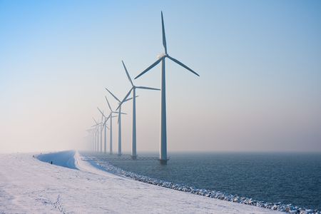 Long row of Dutch windmills disappearing in winter hazeの写真素材