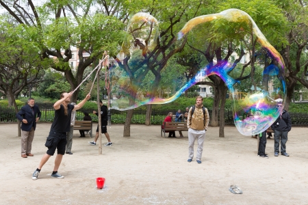BARCELONA - MAY 16: Unknown street artist makes big soap bubbles in a public park on May 16, 2013 in Barcelona, Spainのeditorial素材