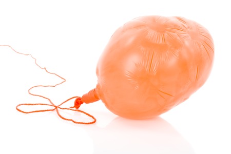 Deflated orange balloon at a rope; isolated over white backgroundの写真素材