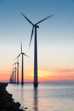 Long row Dutch offshore wind turbines at beautiful sunsetの写真素材