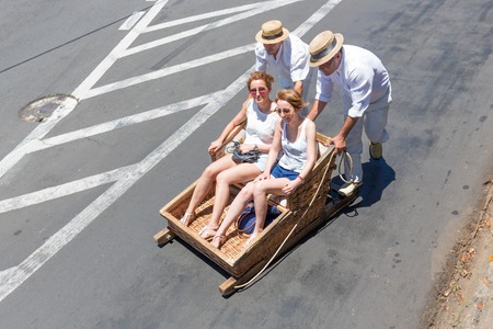 FUNCHAL, MADEIRA - AUG 13: Traditional downhill sledge trip on August 13, 2014 in Madeira, Portugal. Cane sledges were used as traditional local transport. Currently these Toboggan riders are a touristic attraction.のeditorial素材