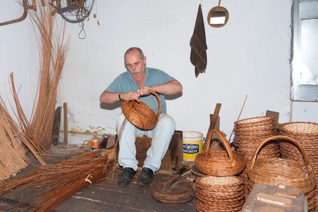 CAMACHA, PORTUGAL - AUG 12: A man is making reed baskets in a braiding factory on Augustus 12, 2014 at Madeira, Portugal. This is a touristic attraction with demonstrations of this traditional craftmanship.のeditorial素材