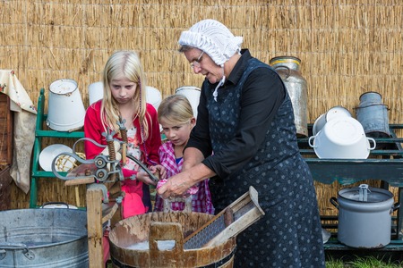 NIEUWEHORNE, THE NETHERLANDS - SEP 27: Farmer woman shows two children the use of a traditional washhub during the agricultural festival Flaeijel on September 27, 2014, the Netherlandsのeditorial素材