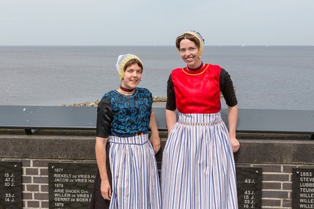 URK, THE NETHERLANDS - JUN 07: Two traditional dressed women from Urk visiting the monument of drown fishermen on June 07, 2014 at the coast of Urk, the Netherlandsのeditorial素材