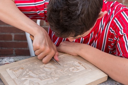 URK, THE NETHERLANDS - JUN 07: A boy in traditional clothes from Urk is making a wood carving on June 07, 2014 in Urk, the Netherlandsのeditorial素材