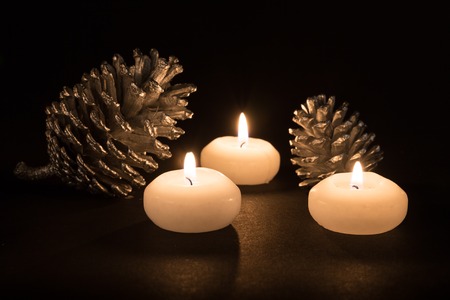 Burning candles with pine apples on a black backgroundの写真素材
