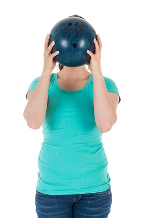 Woman is holding a bowling ball just before her head, isolated over whiteの写真素材