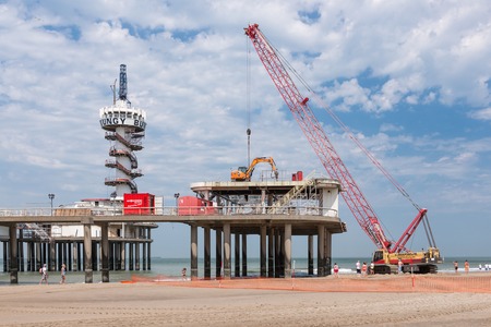 SCHEVENINGEN THE NETHERLANDS JUN 05: Crane and other construction equipment for renovating the famous Pier of Scheveningen on June 5 2015 at the beach of Scheveningen the Netherlandsのeditorial素材