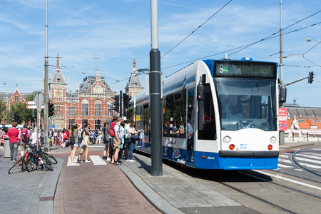 AMSTERDAM, THE NETHERLANDS - AUG 06: Tourists walking in front of the central station of Amsterdam near a tram on August 06, 2015 in Amsterdam, capital city of the Netherlandsのeditorial素材