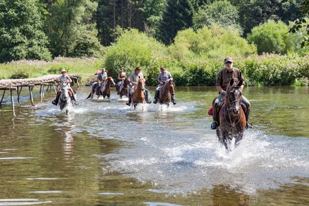 LAFORET, BELGIUM - AUG 15: Riders and horses crossing the river Semois on August 15, 2016 near Laferet, Belgiumのeditorial素材
