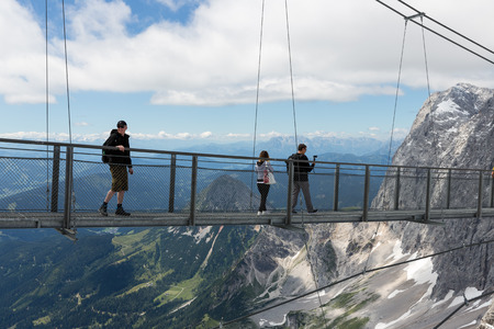 DACHSTEIN MOUNTAINS,  AUSTRIA - JULY 17, 2017: Dachstein Mountain in Austria with hikers passing a skywalk rope bridgeのeditorial素材