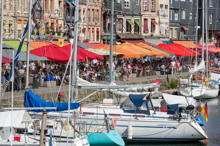 HONFLEUR, FRANCE - AUGUST 24, 2017: Harbor of historic city Honfleur with moord sailing ships. Many tourists enjoy the sunny weather and take a lunch at an outside terraceのeditorial素材
