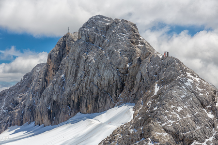 Austrian Dachstein mountain peak with glacier and clouds surrounding the topの写真素材