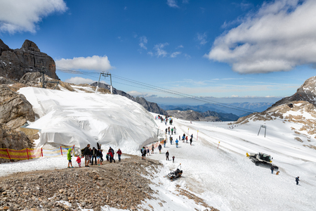 DACHSTEIN MOUNTAINS, AUSTRIA - JULY 17, 2017: Dachstein Mountain in Austria with hikers exploring the top of the glacier with machines preparing the ski pisteのeditorial素材
