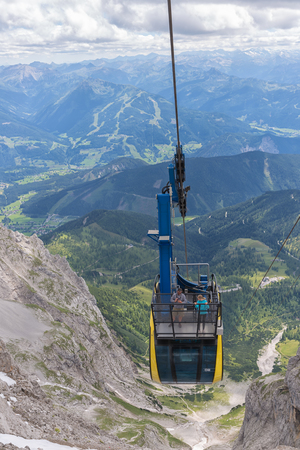 DACHSTEIN MOUNTAINS, AUSTRIA - JULY 17, 2017: Aerial view cable car approaching the Dachstein glacier mountain station in Austria. Some people are standing at the balcony at the roof of the cable carのeditorial素材
