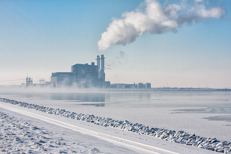 Dutch frozen lake covered with haze and view at a power plantの写真素材