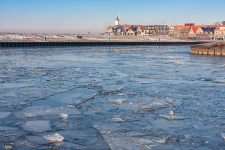 Dutch fishing village Urk in winter with frozen harbor and view at the lighthouseの写真素材