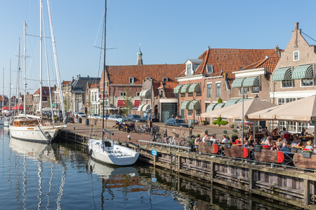 Enkhuizen, The Netherlands - April 20, 2018: Sailing ships in harbor of Enkhuizen with people relaxing at terraceのeditorial素材