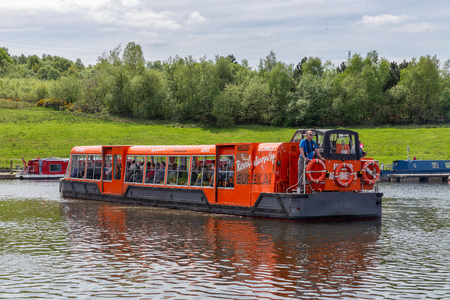 Falkirk, Scotland - May 19, 2018: Launch with tourists near the Falkirk Wheel, rotating boat lift in Scotland, which connects the Forth and Clyde Canal with the Union Canal.のeditorial素材