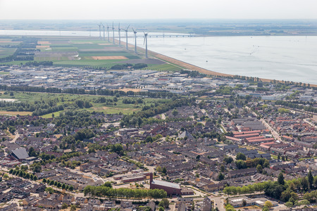 Aerial view Dutch fishing village with new build residential area and wind turbines along the coast