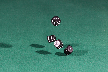 Four black dices falling on a isolated green table