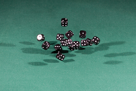 Fifteen black dices falling on a isolated green table