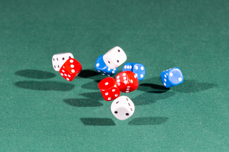 Nine white, red and blue dices falling on a isolated green tableの写真素材