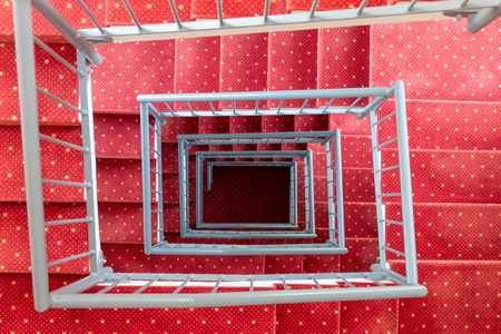 Top view in symmetric stairwell with red carpet and steel parapetの写真素材