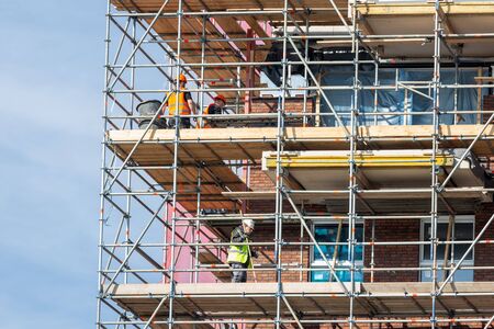 Lelystad, The Netherlands - April 5, 2019: Construction site of new apartment building with scaffolding and busy mason workersのeditorial素材