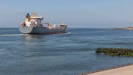 Dutch waterside of Vlissingen with a cargo ship sailing close to the coastの写真素材