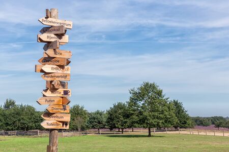 Ermelo, The Netherlands - August 23, 2019: Pole with wooden arrow signs to several interesting...