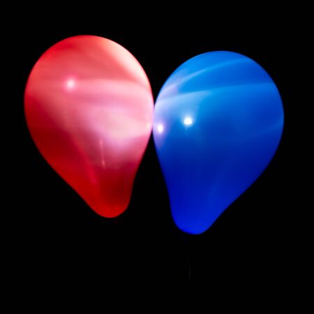 Red en blue helium balloons illuminated with intern LED light against a dark background