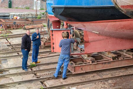 Urk, The Netherlands - September 07, 2019: Workers repairing rudder of ship at shipyard in Dutch fishing village Urkのeditorial素材