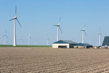 Dutch empty farmland with farmhouses and wind turbinesの写真素材