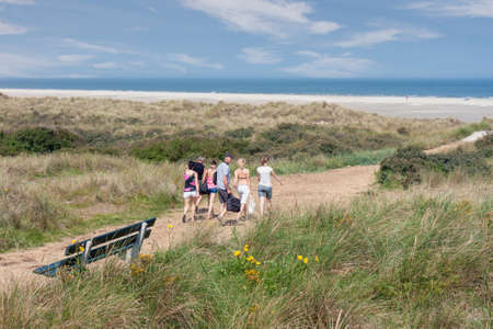 Ameland, The Netherlands- August 02, 2011: Seaside visitors walking over sandy path through dunes to beach of Dutch island Amelandのeditorial素材