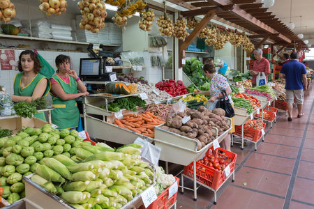 Funchal at Madeira, Portugal - August 01, 2014: Two female vendors selling fresh vegetables at famous market Mercado dos Lavradores in Funchal, capital city of Madeira Island, Portugalのeditorial素材