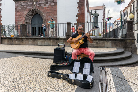 Funchal at Madeira, Portugal - August 01, 2014: Busker playing guitar downtown Funchal at Madeira Island, Portugalのeditorial素材