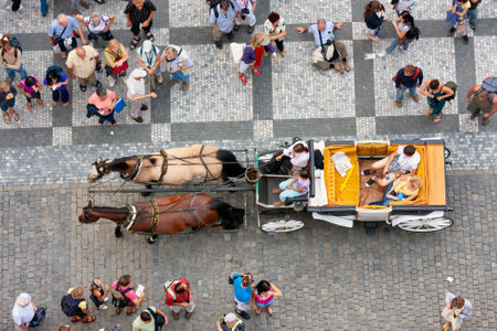 Praha, Czech Republic - Juli 21, 2009: Looking downward from tower Old Town Hall. A carriage with two horses is passing through the people at the Old Town Squareのeditorial素材