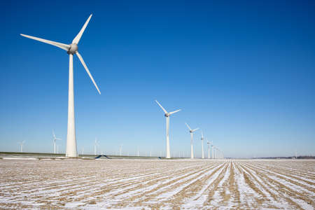 Dutch agricultural landscape wind turbines and fields covered with snow in winter time