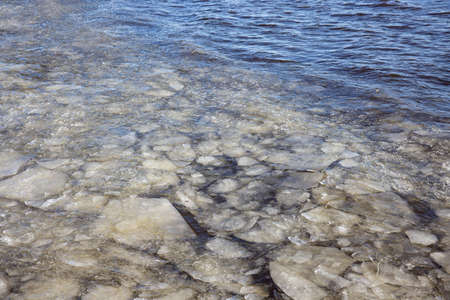 Dutch winter with view at sea covered with drift ice and waves