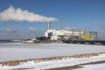 Lelystad, The Netherlands - Februari 12, 2021: Powerplant working at natural gas near frozen Dutch sea at Lelystadのeditorial素材