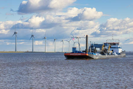 Dredge ship at Dutch sea IJsselmeer near coast with windturbinesのeditorial素材
