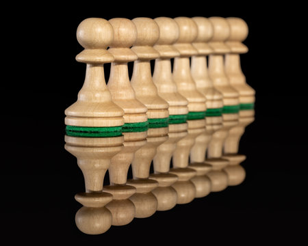 Diagonal line of wooden chess pawns isolated at dark backgroundの写真素材